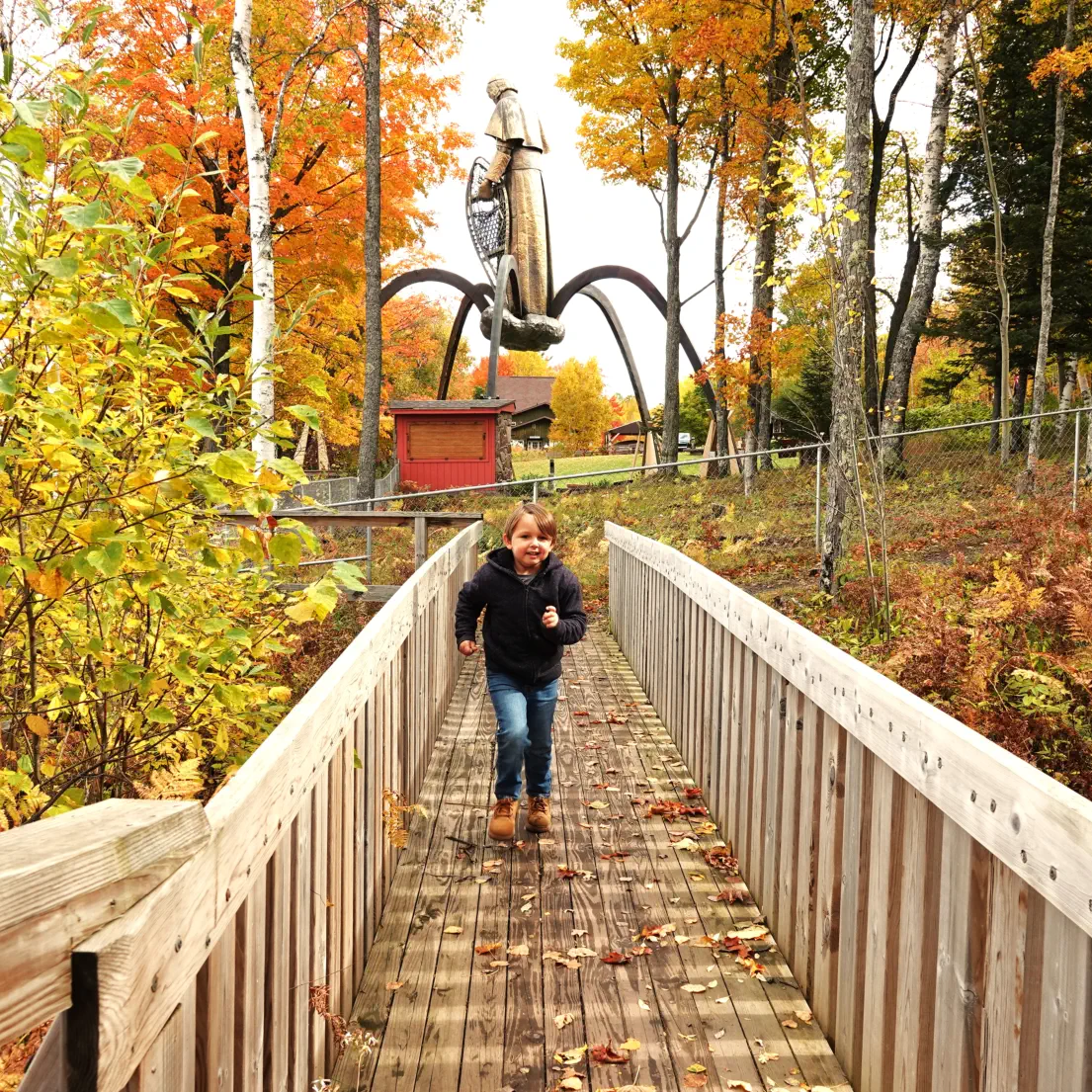 Boy running across bridge with statue in background Boy running across bridge with statue in background